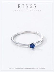 Macro shot of minimalist silver band with a round blue sapphire and small clear zircon