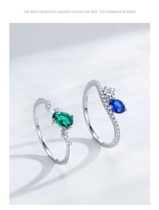 Detail of S925 sterling silver rings featuring emerald and sapphire oval gemstones