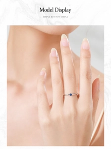 Detail of minimalist silver ring with round blue sapphire worn on model finger