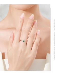 Detail of S925 silver ring featuring emerald gemstone and small diamond on model hand