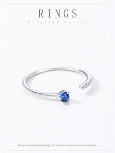 Detail of minimalist 925 silver open ring with round blue gemstone and side diamonds