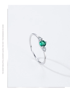 Macro shot of silver ring with round emerald center stone and side zircon accents