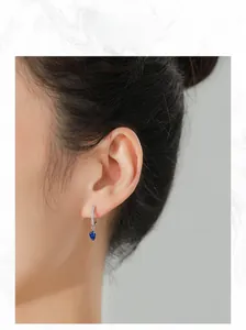 Dettaglio di orecchini a goccia in argento 925 con pendenti blu zaffiro indossati dal modello