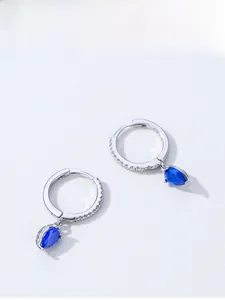 Dettaglio macro di orecchini a cerchio in argento S925 con gemme blu a goccia e diamanti
