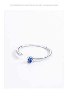 Detail of 925 sterling silver open ring with blue gemstone and micro-pave zirconia