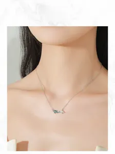 Close-up of 925 silver koi fish necklace with green zircons and pearl on model