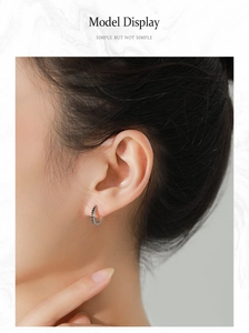 Close-up of silver earrings featuring black V-shaped arrow engraving for women