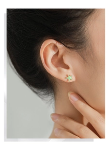 Detail shot of light green starfish stud earrings with small crystals on model's ear
