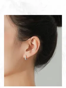 Close-up of S925 silver hoop earrings with LOVE engraving worn by a fashion model