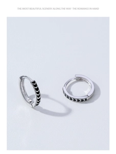 Macro view of silver hoop earrings with black enamel V-shape patterns for women