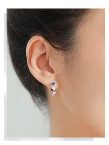 Close-up of 925 silver stud earrings with colorful enamel hearts on a female model
