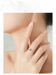 Detail of sterling silver evil eye chain ring with blue enamel charm on model's finger