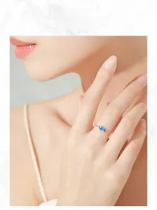 Model wearing a delicate S925 silver chain ring with a blue enamel fish pendant charm