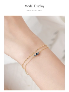 Close-up of double-layered 925 silver gold bracelet featuring three blue zircons on wrist