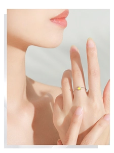 Detail of yellow enamel star on silver chain ring worn on finger by female model