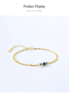 Detail of adjustable gold 925 silver bracelet with three blue zircon stones on light background