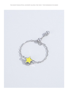 Detail of adjustable silver chain ring featuring a yellow star and slider bead