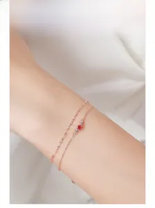 Detail of rose gold double-layered silver bracelet with red ruby and blue stones