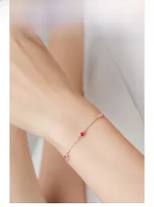 Makroansicht des roségoldenen Armbands mit rosa und roten Edelsteinen am Handgelenk
