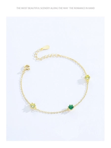Detailed macro view of S925 silver gold bracelet featuring green and yellow zircons