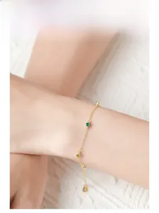 Close-up of a 925 silver gold bracelet featuring three elegant green gemstones on a model wrist