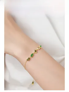 Macro detail of gold-plated 925 silver bracelet featuring multi-cut green gemstones