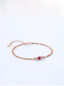 Detailed view of rose gold layered bracelet with red gemstone and pink crystals