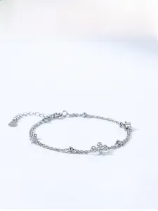 Macro detail of S925 sterling silver double-layer bracelet with sparkling clover charm
