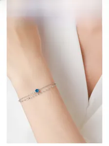 Gros plan d'un bracelet en argent avec pendentif zircon bleu sur un poignet