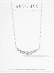 Macro shot of silver curve necklace featuring seven graduated cubic zirconia stones