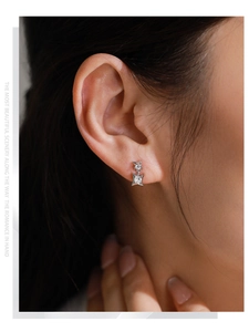 Detail of silver S925 star earrings with white zircon on a model's ear