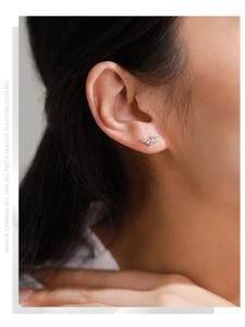 Macro detail of S925 sterling silver wing earrings with inlaid cubic zirconia on a model