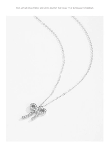 Macro shot of silver bow pendant featuring sparkling zircon stones on a delicate chain