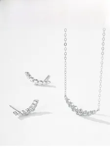 Detailed view of silver curved arc jewelry set with shimmering cubic zirconia stones