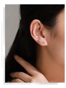 Detail of curved silver ear crawler earrings with pavé cubic zirconia on model
