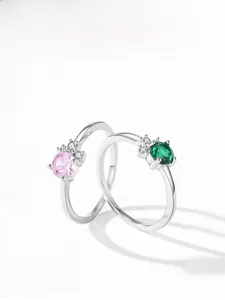 Detailed view of silver rings with round pink and green zircon stones and micro diamonds