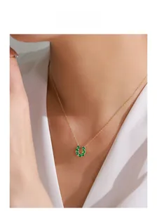 Gros plan du collier fer à cheval doré avec sept zircons verts sur le cou du modèle