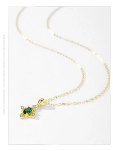 Gros plan d'un collier doré avec gemme verte ovale et zircons en forme d'étoile