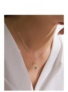 Detail of a gold sunburst pendant necklace with a purple rectangular crystal on model