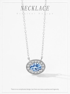 Gros plan d'un pendentif ovale avec pierre bleue et halo de zircon sur chaîne argent