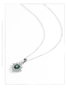 Detail of emerald cut green gemstone pendant with micro-paved diamond floral halo