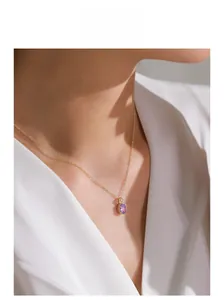 Elegant gold necklace with oval purple crystal pendant worn on neck for a luxury look