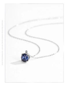 Detail of silver necklace featuring a large deep blue faceted round gemstone pendant