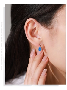 Vue détaillée d'une boucle d'oreille en argent S925 avec zircon bleu sur le modèle