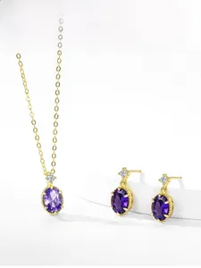 Detail shot of gold necklace and earring set with oval purple crystal and small diamonds