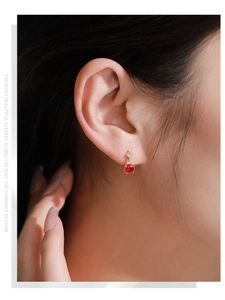 Detailed view of gold S925 sterling silver earrings with red zircon and clear accent stone