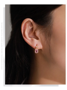 Detail of pink rectangular step-cut zircon earrings with gold plating on a model