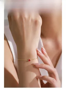 Detail of a gold-plated S925 silver bracelet featuring a round red zircon on a female wrist
