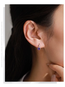 Close-up of elegant S925 sterling silver stud earring with violet zircon on female model