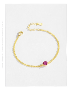Detail of gold double-chain silver bracelet with faceted round purple crystal and lobster clasp